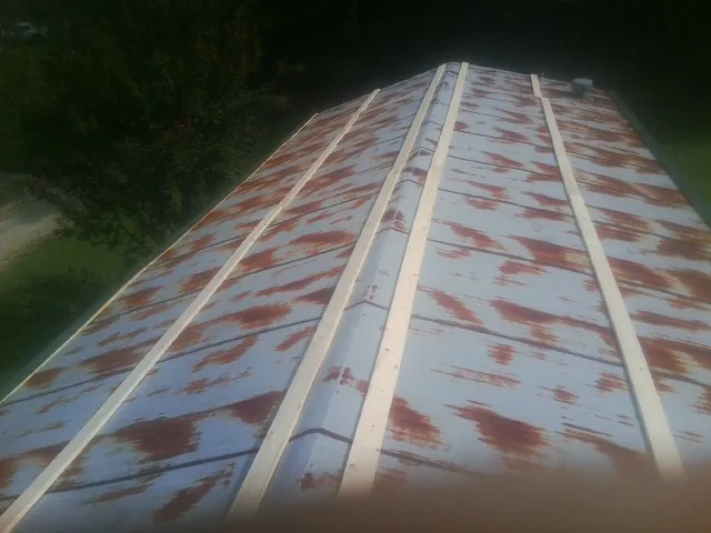 Rusted metal roof panels with new wood purlins before replacement — Storm Damage Roof Repair in Hollandale by Roofing Brothers