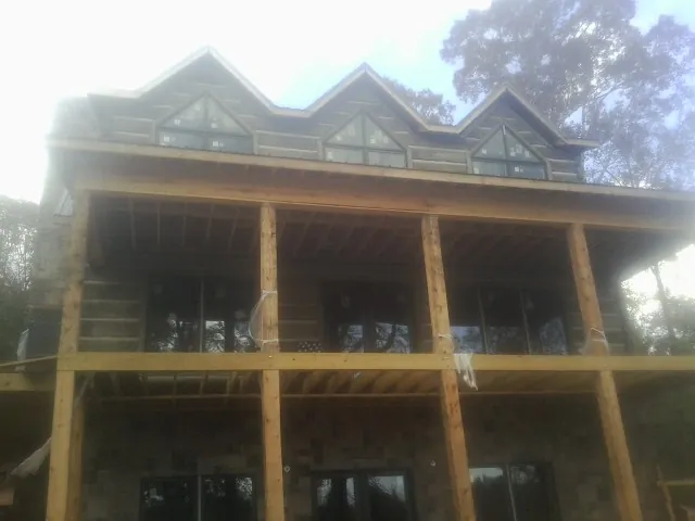 Dormers and porch framing on a large log home under construction — Roof Coating work by our crew in Hollandale