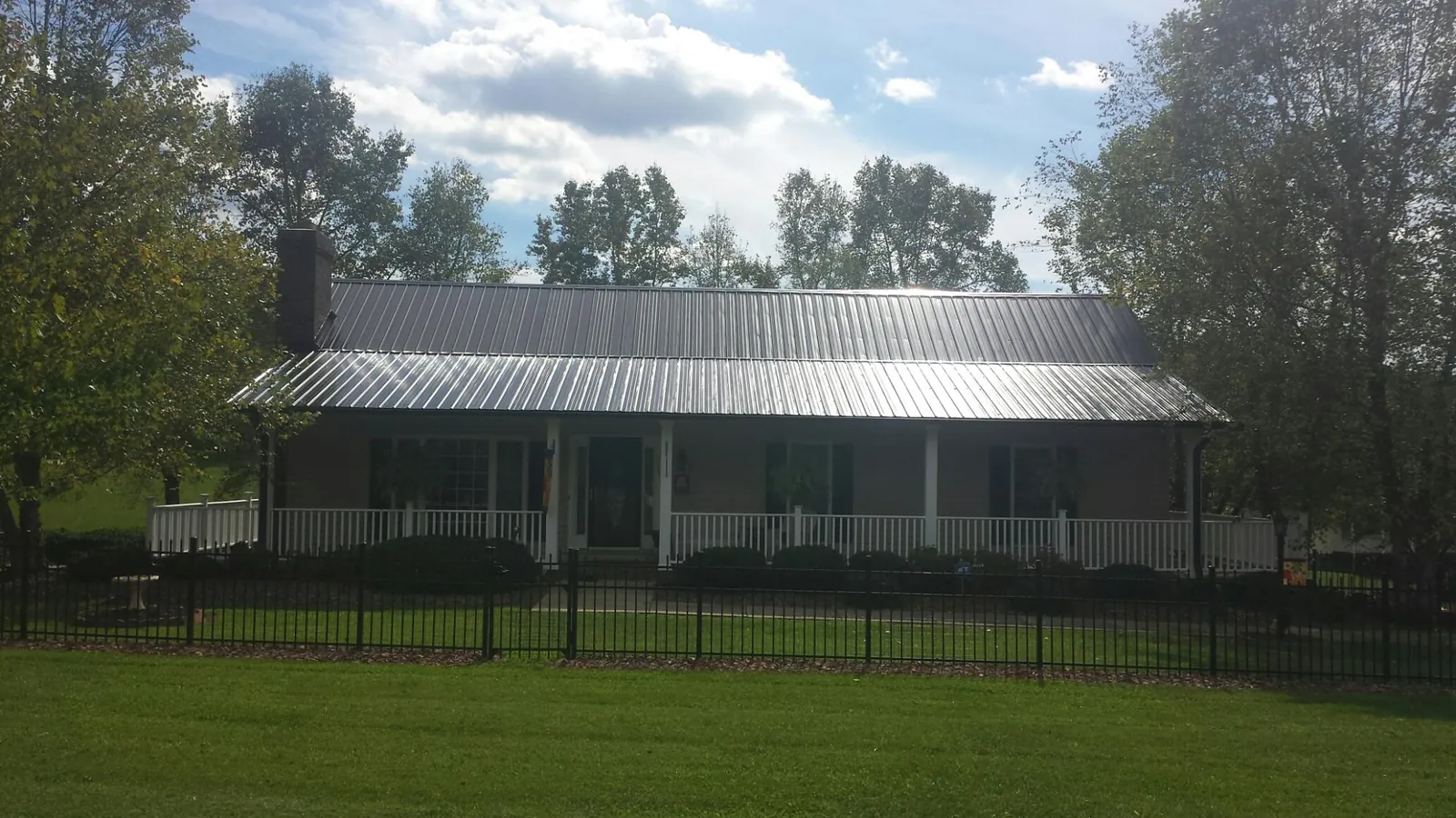 Gray metal roof on a brick ranch with a full width front porch — Gutter Guard Installation work by our crew in Hollandale